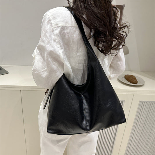 Women's large-capacity PU leather shoulder tote bag in a stylish winter design, shown from the side to highlight spacious int