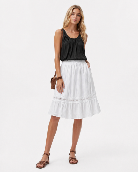 A ruffle pleated midi skirt in classic black with an elastic waist, styled for casual resort and everyday wear, featuring a feminine pleated silhouette and minimalist aesthetic.