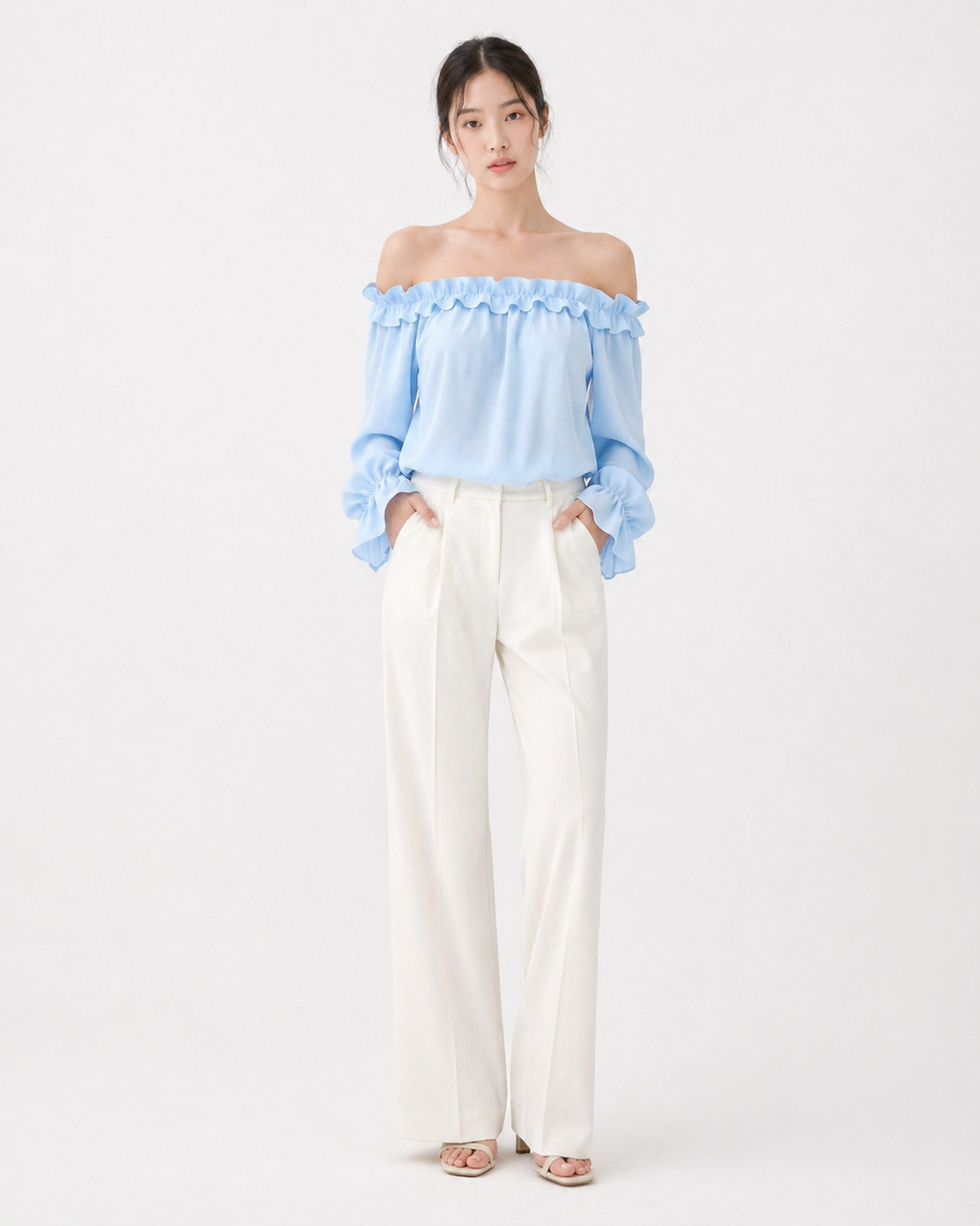 Woman wearing a white ruffle off-shoulder long sleeve blouse with slim fit silhouette, styled for a chic spring casual look