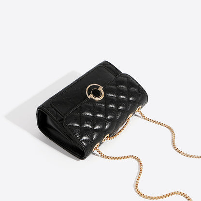 Small black PU leather crossbody bag with gold chain strap, minimalist design, shown from the side angle