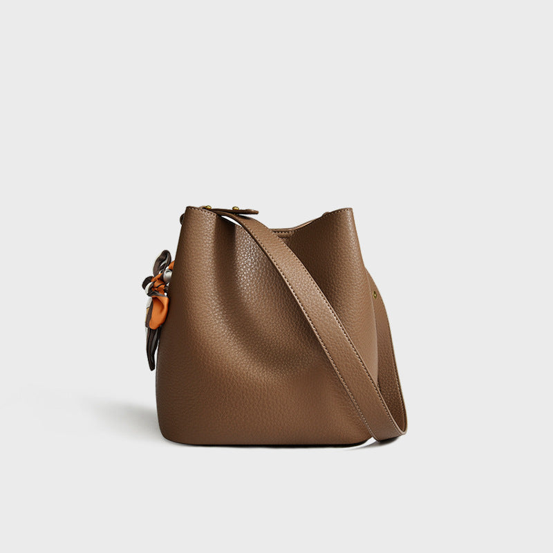 Women's genuine leather bucket crossbody tote bag shown from the side, highlighting the structured silhouette and strap detai