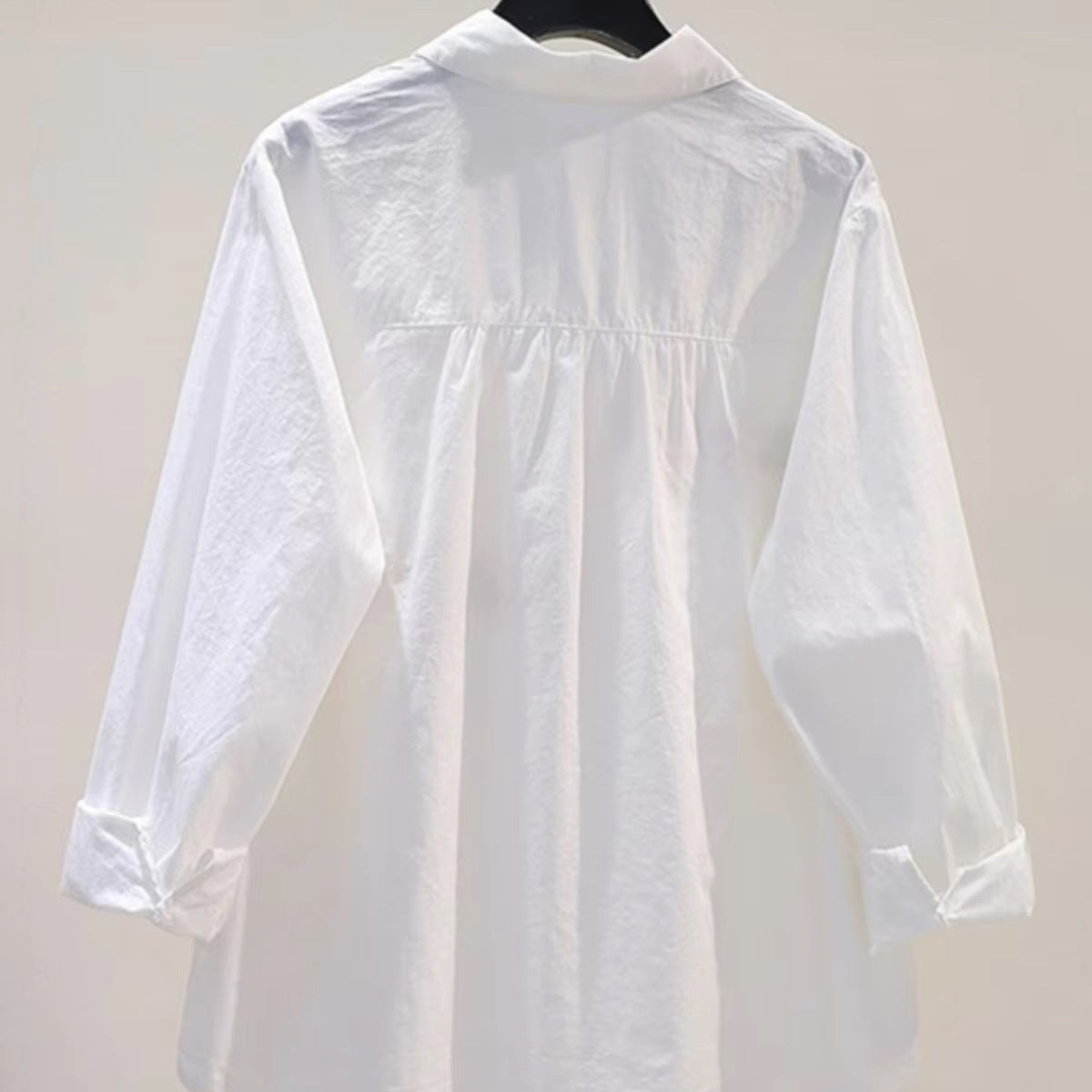 White loose fit cotton blouse with embroidered cartoon detail, shown from a close-up angle highlighting the embroidery design
