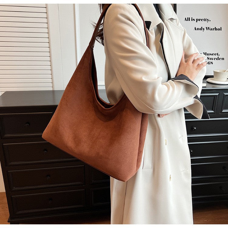 Women's suede tote shoulder bag with magnetic snap closure shown from a side angle highlighting the soft texture and structur