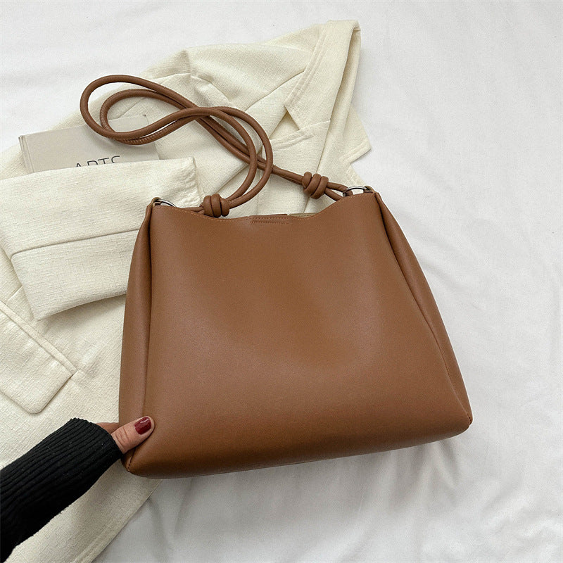 Women's PU leather retro bucket crossbody tote bag in a neutral tone, shown as a stylish commuter purse with adjustable strap