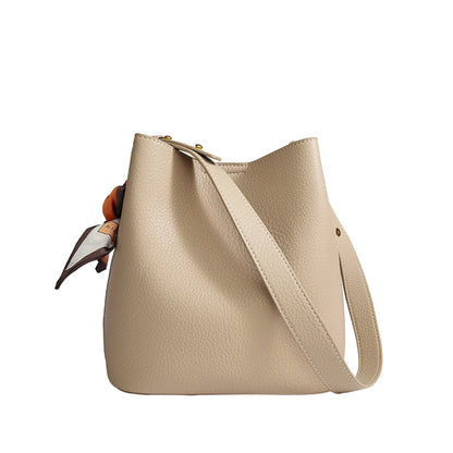 Women's genuine leather bucket crossbody tote bag shown from the side, highlighting the structured silhouette and strap detai