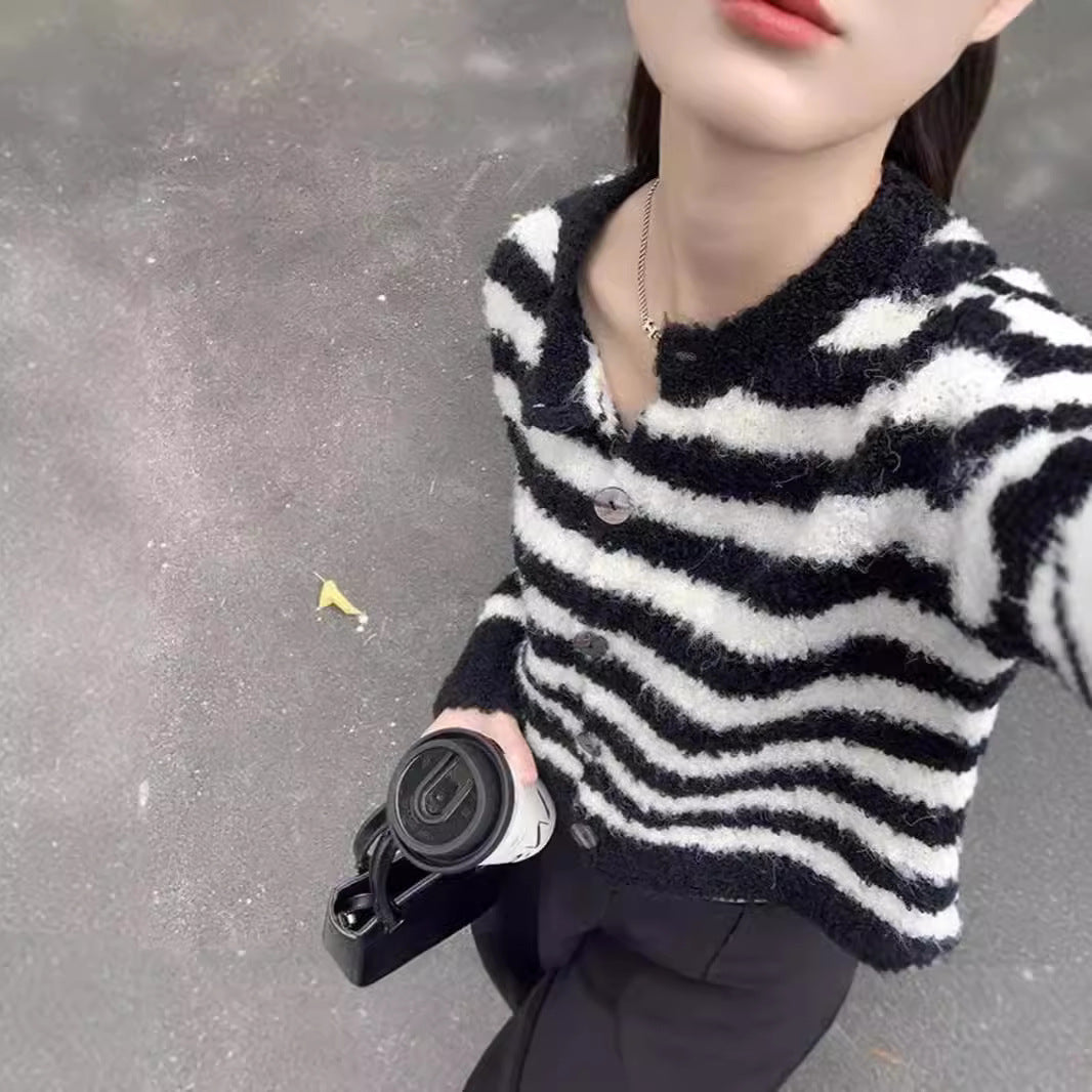 Woman wearing a chunky knit short cardigan sweater with an open front and relaxed fit, styled as a cozy layering piece