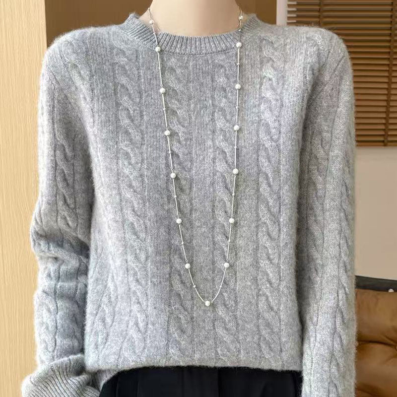 Women's loose cable-knit crewneck sweater in merino wool blend, shown from the back to highlight the textured knit pattern.