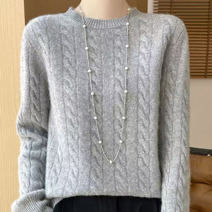Women's loose cable-knit crewneck sweater in merino wool blend, shown from the back to highlight the textured knit pattern.