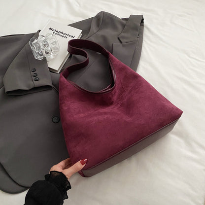 Women's suede tote shoulder bag with magnetic snap closure, shown from the side to highlight texture and strap length