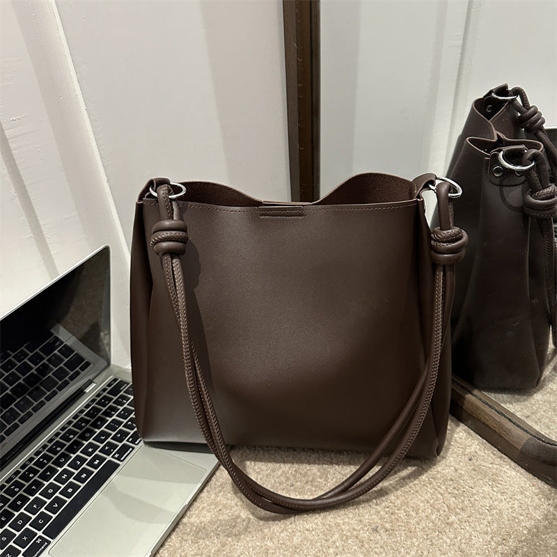 Women's PU leather retro bucket crossbody tote bag in a neutral tone, shown from a side angle highlighting the strap and stru
