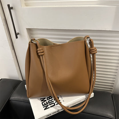 Women's PU leather retro bucket crossbody tote bag in a neutral tone, shown from a side angle highlighting the strap and stru