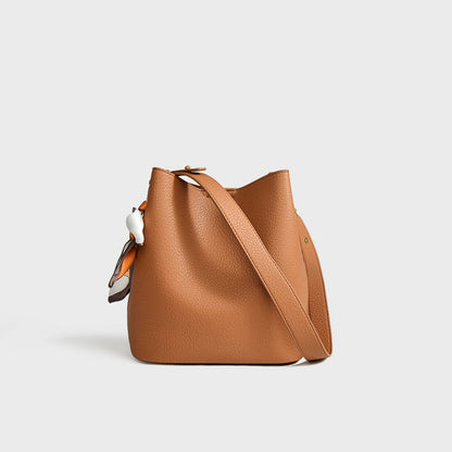 Tan genuine leather bucket crossbody tote bag showing interior compartment and adjustable strap detail