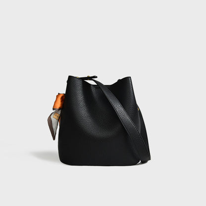 Women's genuine leather bucket crossbody tote bag shown from the side, highlighting the structured silhouette and adjustable 
