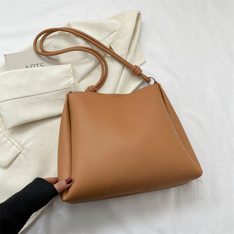 Women's PU leather retro bucket crossbody tote bag in a neutral tone, shown as a stylish commuter purse with structured silho