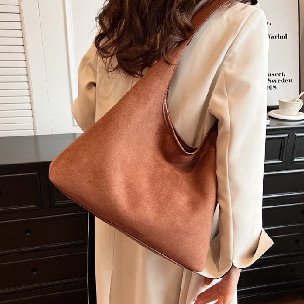 Women's suede tote shoulder bag with magnetic snap closure, shown in a soft neutral tone with structured silhouette