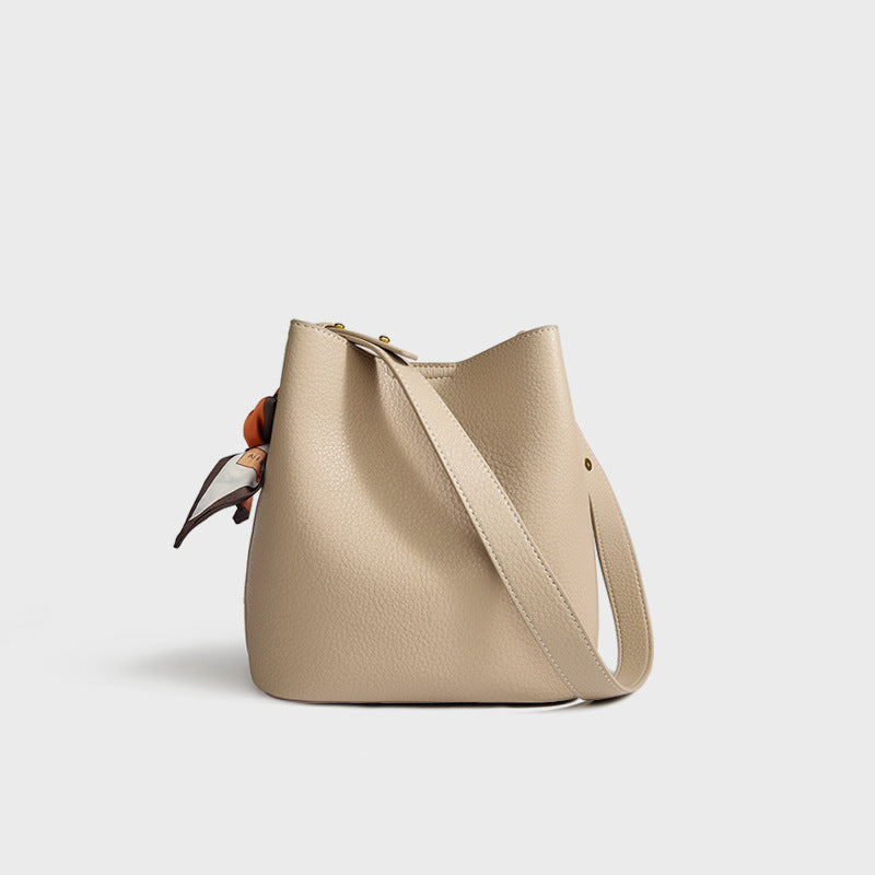 Women's genuine leather bucket crossbody tote bag shown from the side, highlighting the structured silhouette and strap detai